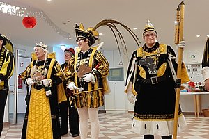 Fünf Personen in bunten Kostümen für einen festlichen Anlass in einem dekorierten Raum.